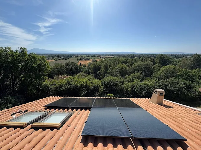 Panneaux Solaires sur Toiture en Tuiles et Vue Paysage Installation de panneaux solaires sur toit en tuiles face à un paysage verdoyant sous un ciel ensoleillé.